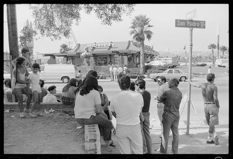 A crowd of people watches the scene outside the McDonald's restaurant in which a lone gunman killed 20 people in San Ysidro, California. (Photo by Bettmann, Getty)