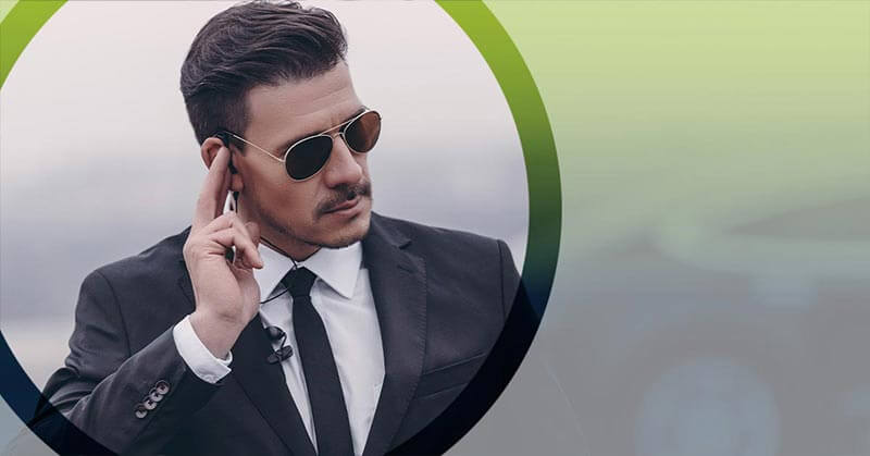 Photo of a male security professional in sunglasses listening into an ear peace.