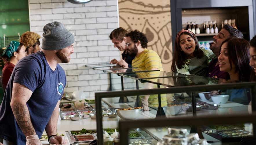 happy people in line to get pizza at MOD Pizza