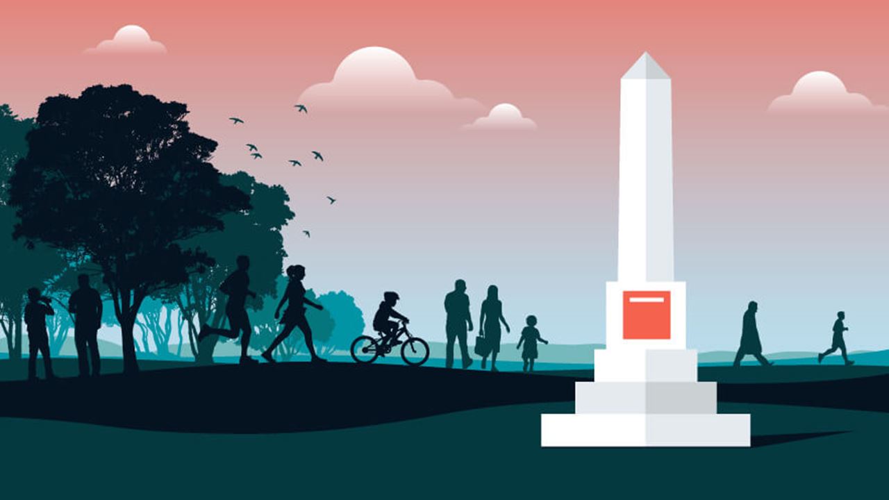Silhouetted people walk, run, and bike in a park at sunset near a tall obelisk memorial monument with a red plaque, surrounded by trees and birds in flight.