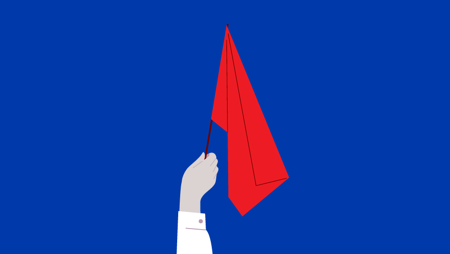 Hand holding red flag on blue background. The effectiveness of red flag laws is being debated after two recent shootings allegedly involved suspects who were known to authorities for other incidents.