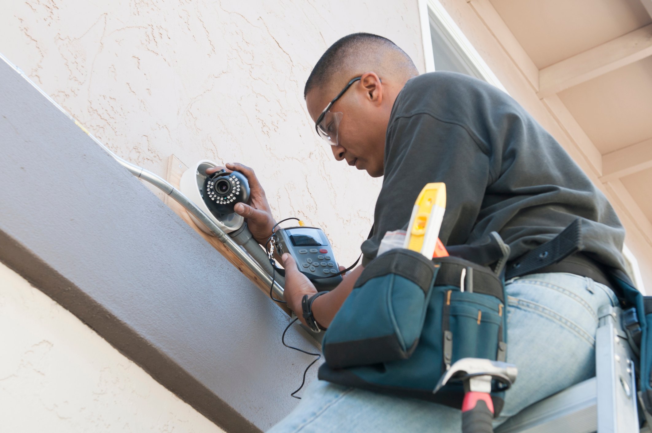 Man installs security camera on the side of a building. How can you enhance your organization’s security systems?