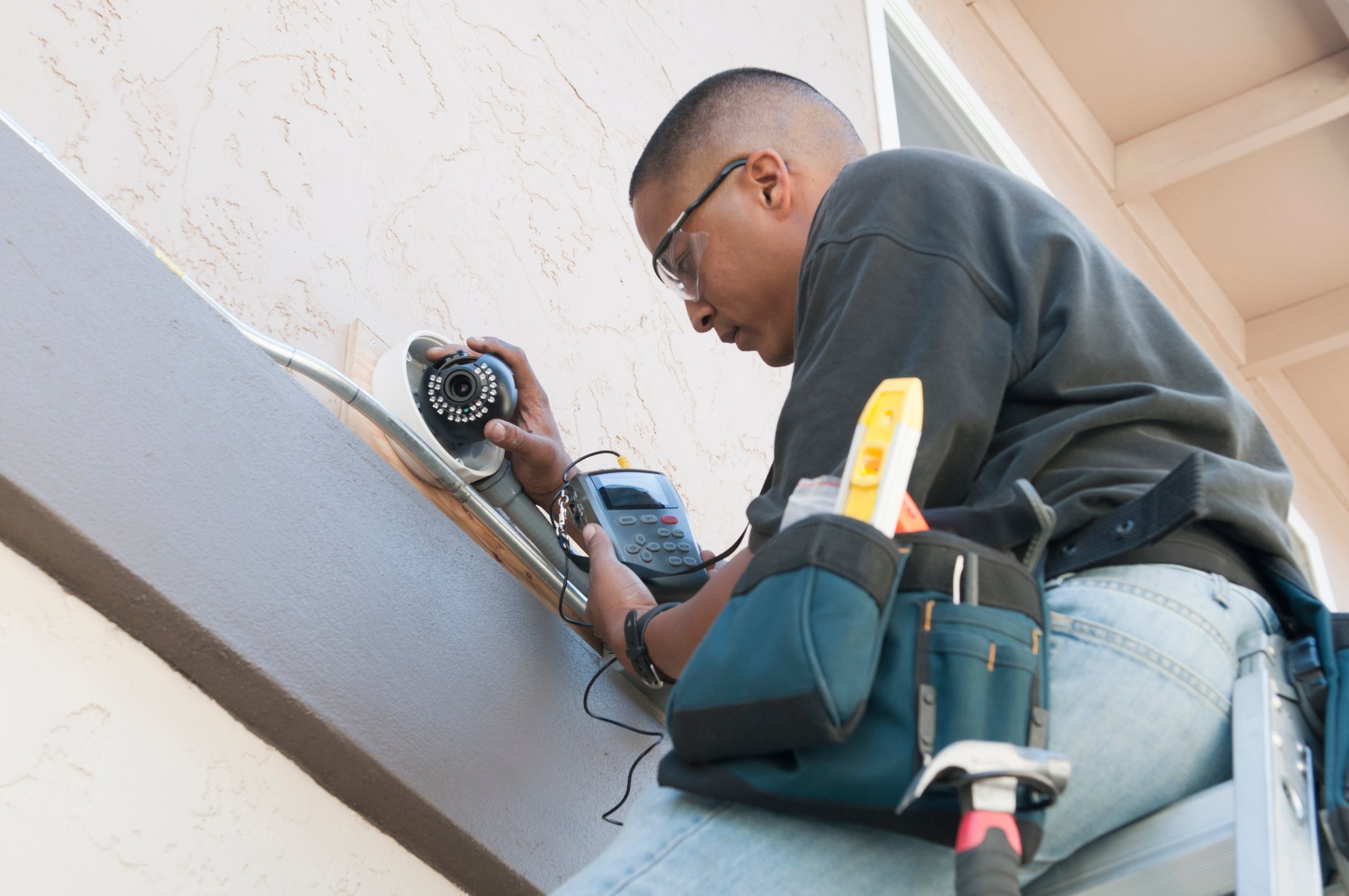 Man installs security camera on the side of a building. How can you enhance your organization’s security systems? 