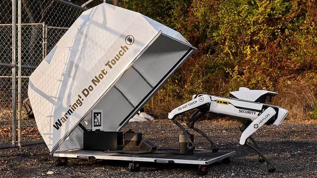 Photo of a Boston Dynamics Spot robot dog stepping out of it's container, in use by Asylon Robotics for patrol near a fence.