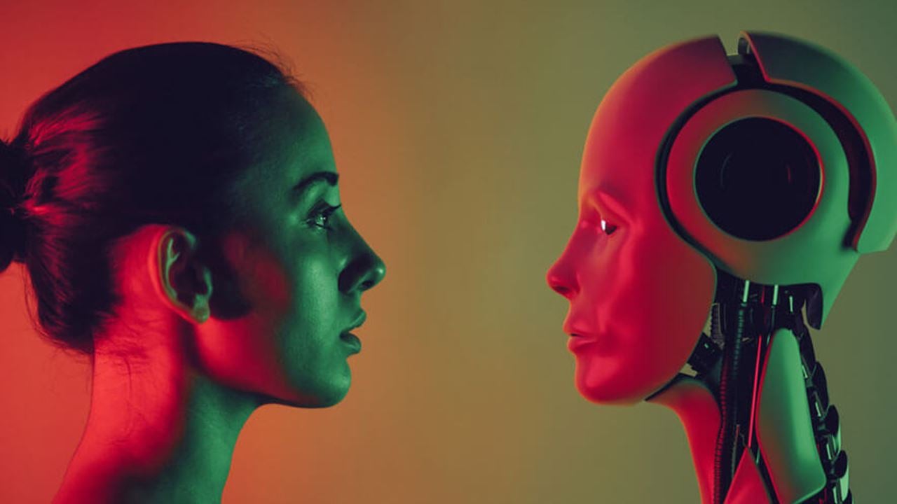 Photo of a profile view of a woman and a robot facing each other.