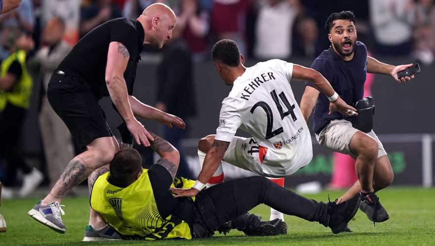 Photo of West Ham United's Thilo Kehrer is accidentally tackled by a security guard as pitch invaders enter the field following the UEFA Europa Conference League Final at Fortuna Arena in Prague.