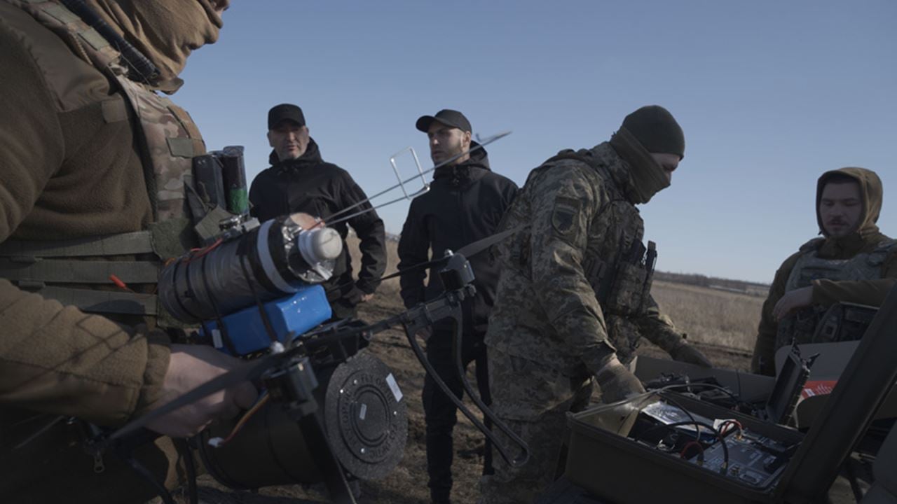 Ukrainian soldiers prepare a fiber-optic drone for deployment while teammates monitor equipment and controls in an open field near the front line in Donetsk Oblast, Ukraine.