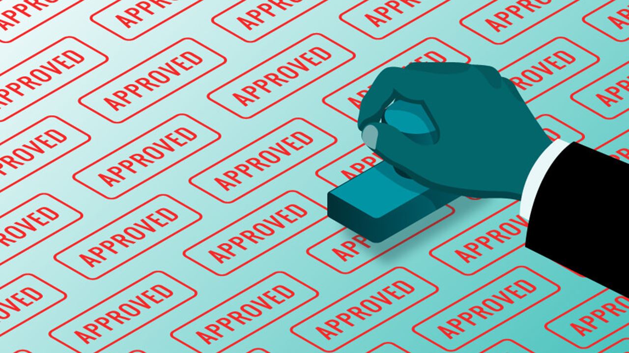 Hand holding a rubber stamp over a surface filled with repeated “APPROVED” marks, symbolizing automated approvals and oversight bias in AI systems