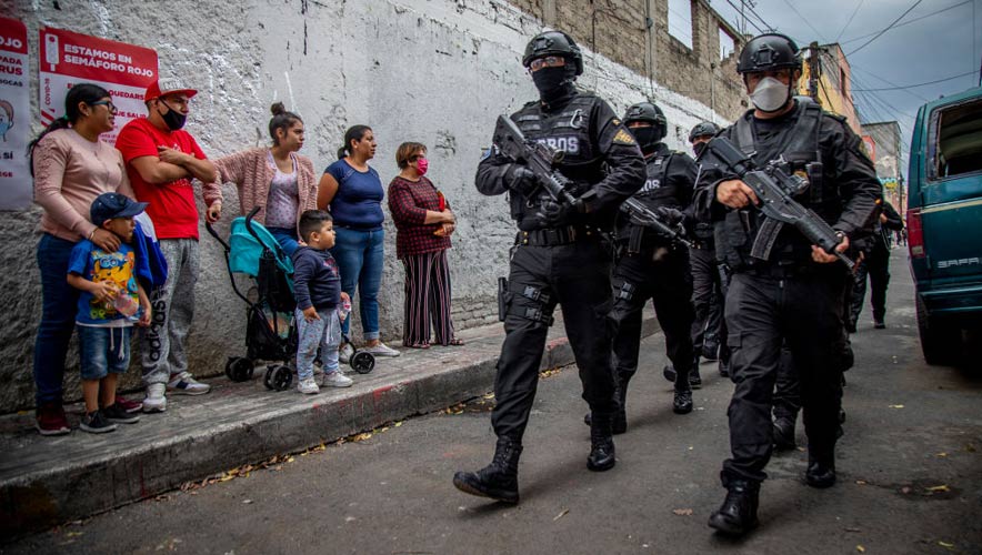 Mexico, Mexiko-Stadt: Women and children look at armed policemen with masks who fight the drug trade in the city.  A new study underscores the continued troubles Mexican authorities have in containing the violence of its drug cartels and associated gangs. The organization Causa en Comun said the country’s news outlets report an average of 17 atrocities each day.
